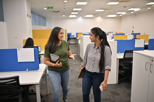 Two colleagues walking and talking in an open-plan office