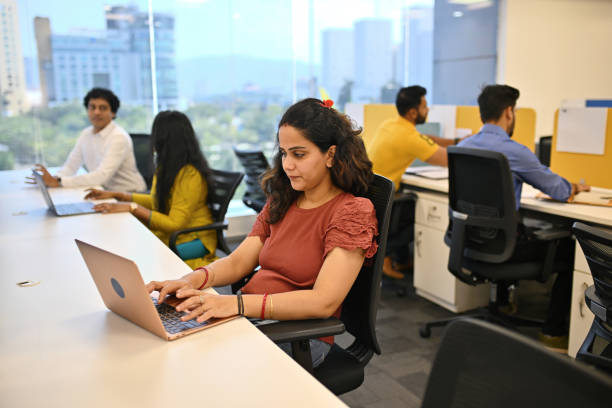 Open-plan office with people working at laptops by the windows