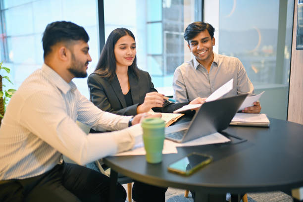 Three colleagues discussing around a round table with a laptop